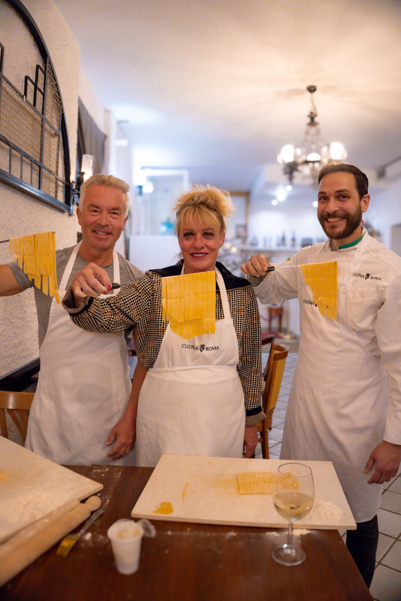 Mani che stendono la pasta fresca all'uovo su un tagliere di legno