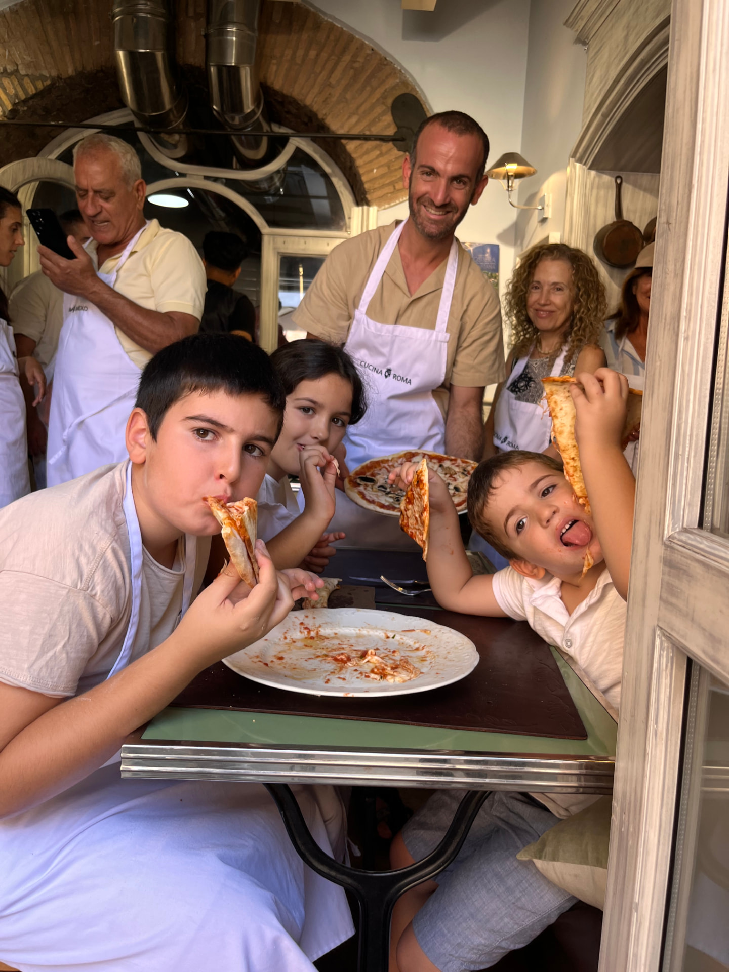 Famiglia con bambini gusta la pizza appena sfornata durante la pizza class per famiglie a Roma